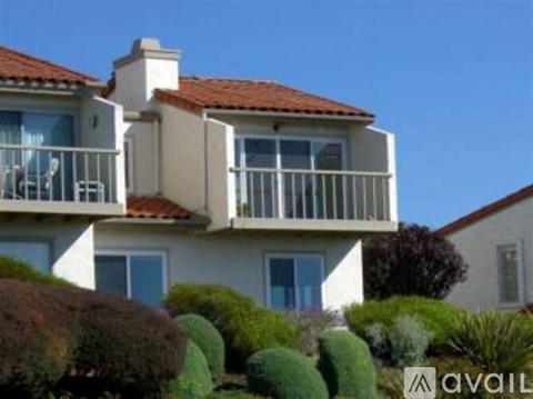 A two-story house with a balcony and a red tile roof.