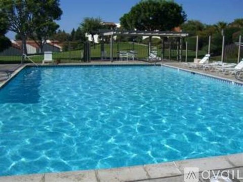 A large swimming pool with a sun lounger and a fence.