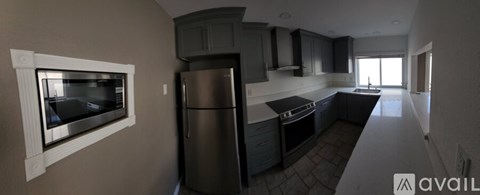 A kitchen with a refrigerator, cabinets, and a microwave.