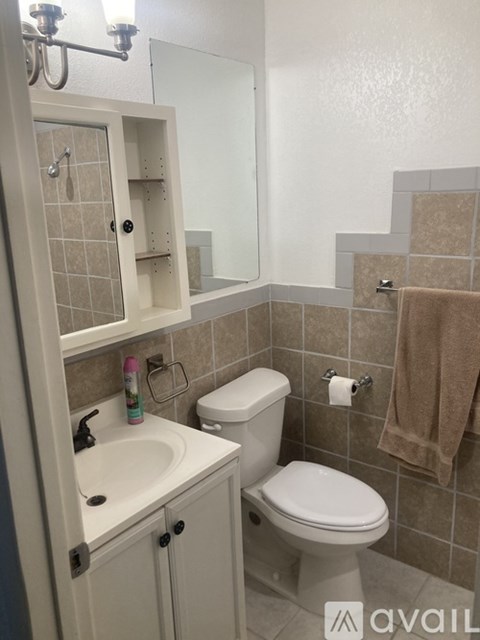 A bathroom with a toilet, sink, and mirror.