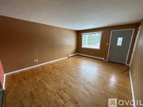 A room with wooden flooring and a window with a view of trees.