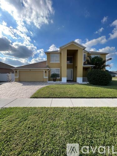 A two-story house with a garage is surrounded by a well-maintained lawn.