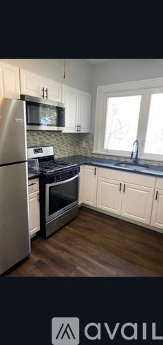 A kitchen with white cabinets and a stainless steel refrigerator.