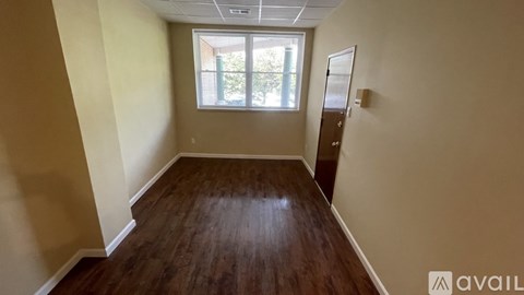 A room with wooden flooring and a window letting in natural light.