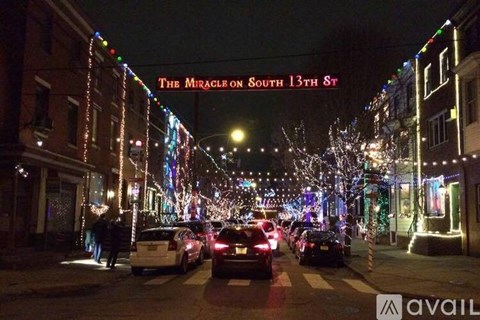 A street with cars parked on the side and a building with the words "The Miracle on South 13th St" on it.
