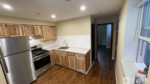 A kitchen with wooden cabinets and a stainless steel refrigerator.