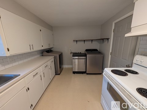 A kitchen with white cabinets and a white stove top oven.