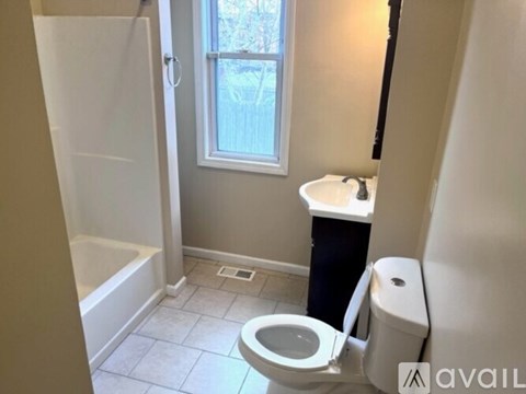 A bathroom with a toilet, sink, and window.