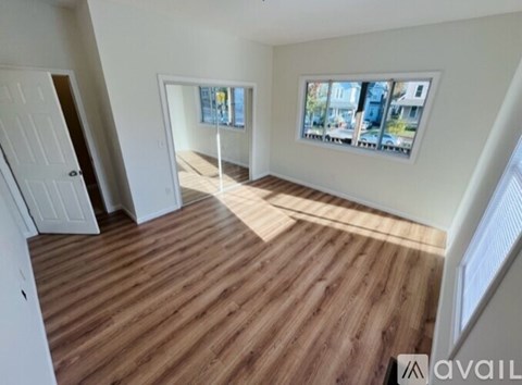 A room with wooden flooring and a window showing a view of buildings outside.
