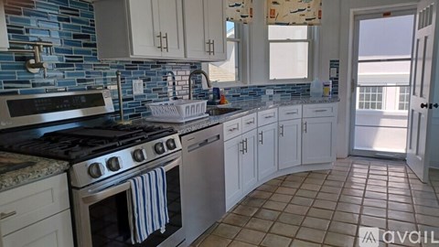 A kitchen with a black stove top oven and white cabinets.