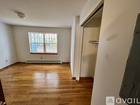A room with wooden floors and a window with a view of trees.