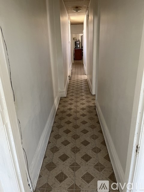 A long hallway with a checkered floor and white walls.