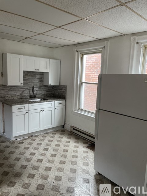 A kitchen with white cabinets and a checkered floor.