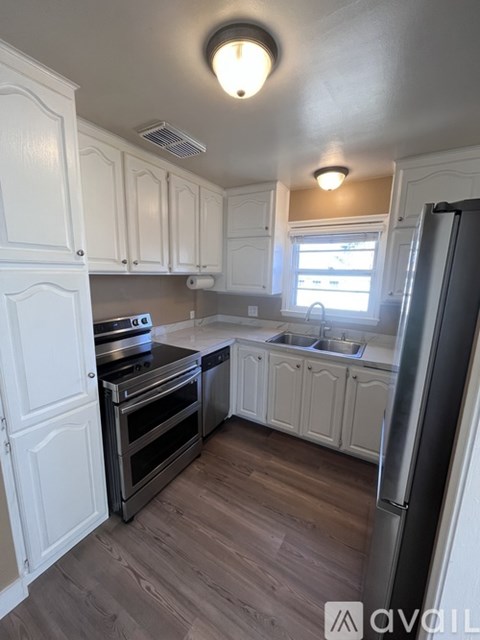 A kitchen with white cabinets and a wooden floor.