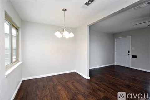 A room with wooden floors and a chandelier hanging from the ceiling.