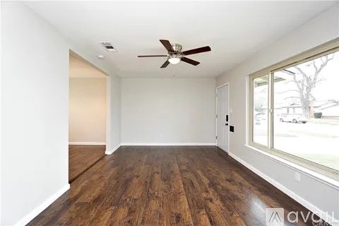 A room with a ceiling fan and wood flooring.