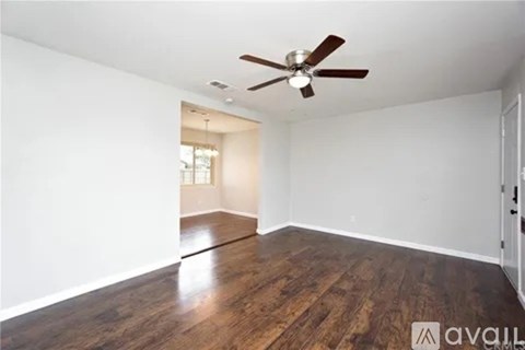 A room with a ceiling fan and wooden flooring.