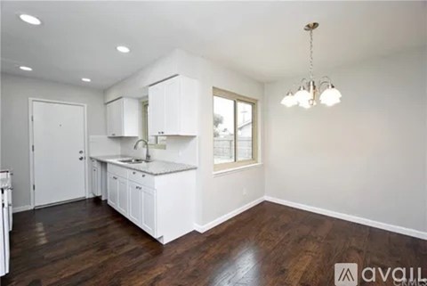 A kitchen with white cabinets and a wooden floor.