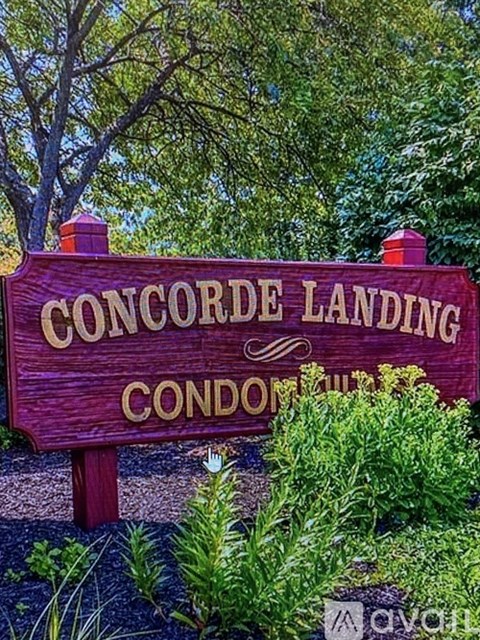 A sign that says Concorde Landing Condos stands in front of trees.