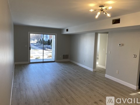 A spacious room with a ceiling fan and sliding glass doors leading to a view of a street.