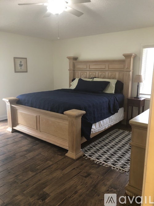 A bedroom with a bed, wooden headboard, and a ceiling fan.