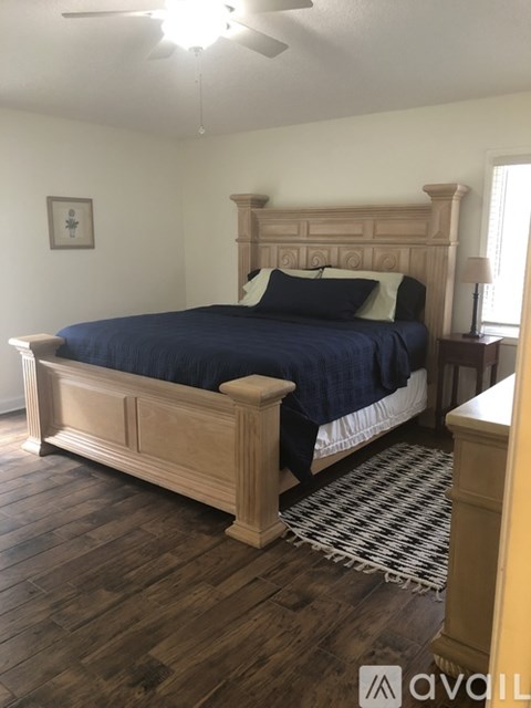 A bedroom with a bed, wooden headboard, and a ceiling fan.