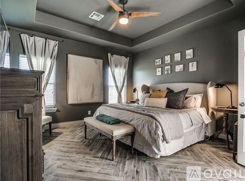 A bedroom with a bed, nightstand, and window with curtains.