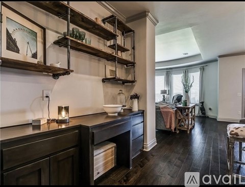A kitchen with dark wood floors and cabinets, a countertop with a bowl and candle, and a dining area with a table and chairs.