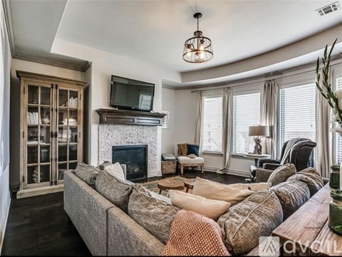 A living room with a grey couch and a fireplace.