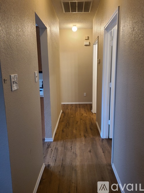 A long hallway with wood floors and white walls.