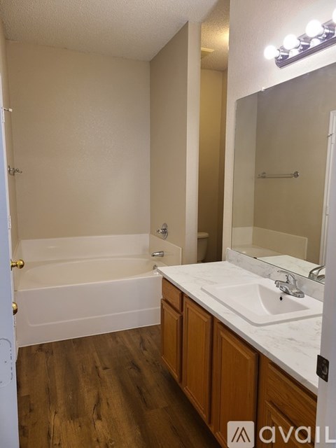 A bathroom with a white tub, sink, and wooden cabinets.