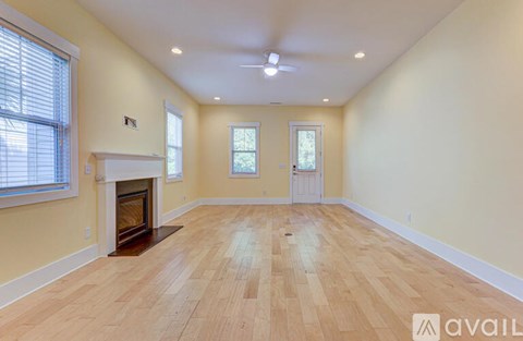 A spacious room with a fireplace and wooden flooring.