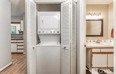 A white oven and microwave are built into a cabinet in a kitchen.