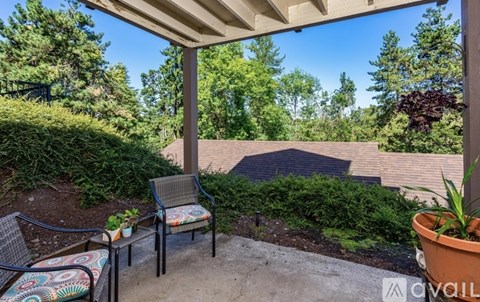 A patio with a chair and table is covered by a roof.