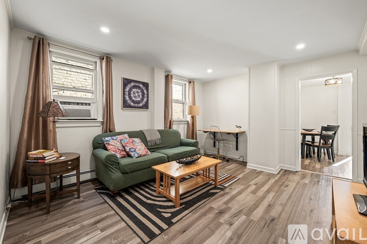 A living room with a green couch and wooden floors.