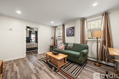A living room with a green couch, wooden coffee table, and striped rug.
