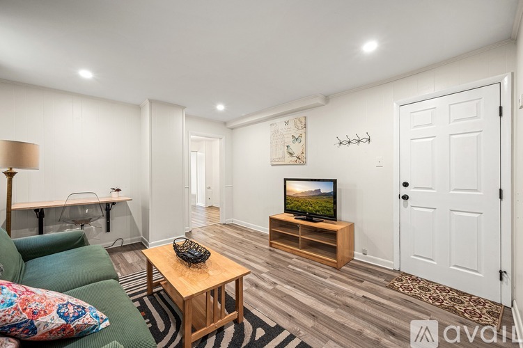 A living room with a green couch, a wooden coffee table, and a flat screen TV on a wooden stand.