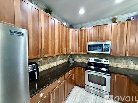 A kitchen with wooden cabinets and a stainless steel refrigerator.