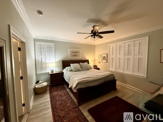 A bedroom with a bed, a ceiling fan, and a rug on the floor.