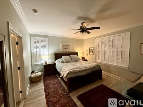 A bedroom with a bed, a ceiling fan, and a rug on the floor.