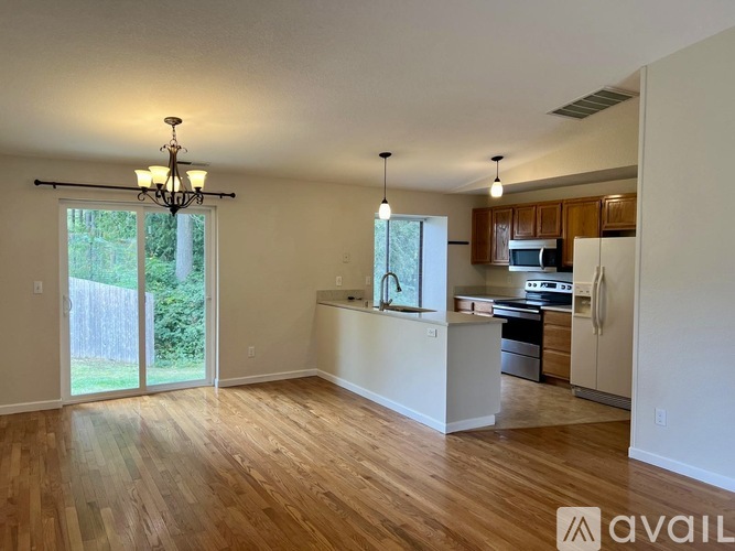 A well-lit, spacious kitchen and living room with wooden floors and white walls.