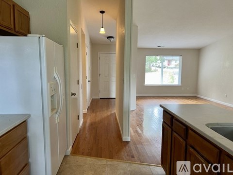 A kitchen with a white fridge and wooden floors.