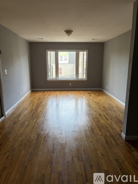 A room with wooden floors and a window letting in sunlight.