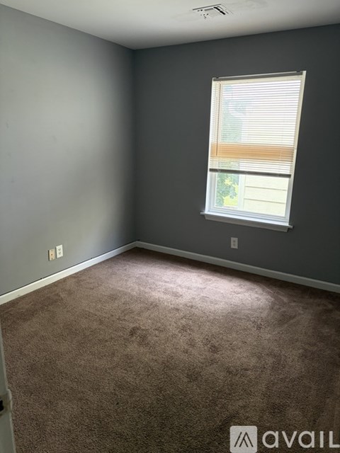 A room with a carpeted floor and a window with blinds.