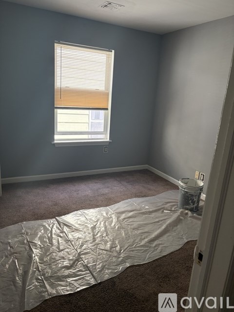 A room with a white bucket on the floor covered in plastic.