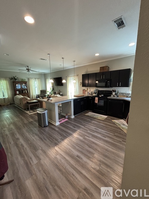 A kitchen with black cabinets and a wooden floor.