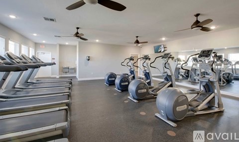 A gym with treadmills, elliptical machines, and a fan.