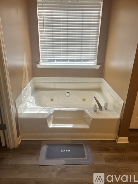 A bathroom with a bathtub and a window with blinds.