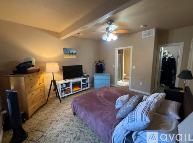 A bedroom with a bed, dresser, and ceiling fan.