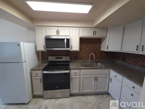 A kitchen with a white refrigerator and a black microwave above the stove.